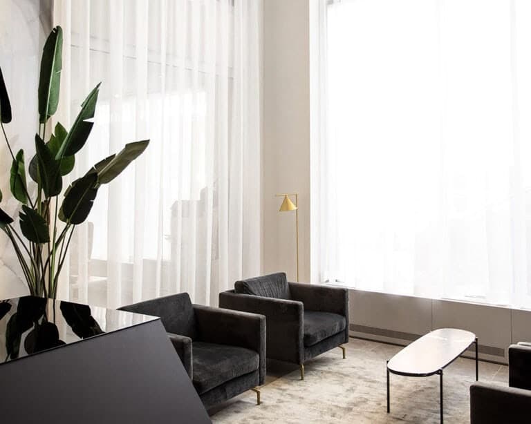 Elegant living room with blockout curtains, black armchairs, and natural light.